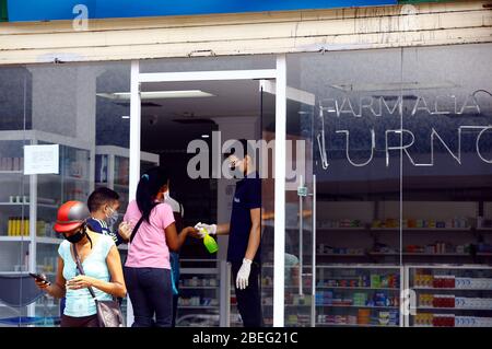 Guacara, Carabobo, Venezuela. April 2020. 13. April 2020. Die Leute stehen am Eingang einer Apotheke an, um Medikamente zu kaufen. Durch vorbeugende Maßnahmen gegen das Coronavirus können bis zu 5 Personen in das Gebäude eindringen und Alkohol wird versprüht, um das mögliche Vorhandensein des Virus zu beseitigen. In Guacara, Bundesstaat Carabobo. Foto: Juan Carlos Hernandez Quelle: Juan Carlos Hernandez/ZUMA Wire/Alamy Live News Stockfoto