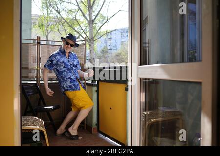 Mann auf dem Balkon seines Hauses, ein Mann in einem Hut, Mann, der auf dem Balkon tanzt Stockfoto