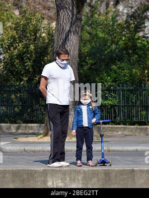 Ein Vater und seine Tochter gehen in Paris durch die Straßen und tragen während der in Frankreich erklärten Quarantäne eine hausgemachte Stoffmaske. Stockfoto