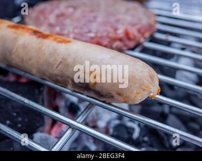 Schweinefleisch und Rindfleisch Burger auf einem Holzkohlegrill mit Nahaufnahme und selektiven Fokus auf die Schweinewurst Stockfoto