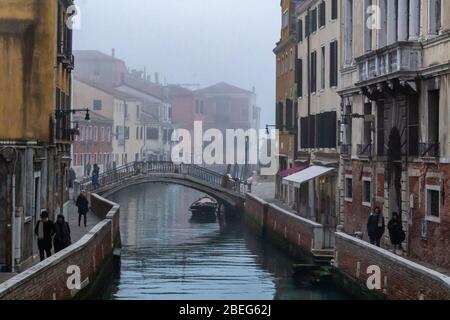 Venedig, Italien. Januar 2019. Menschen, die in der Nähe eines Kanals in Venedig im Nebel spazieren Stockfoto