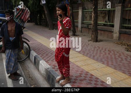 Dhaka, Bangladesch. April 2020. Ein Mädchen benutzt Handy, wenn Rikscha-Abzieher wartet, um zurück zu bekommen, als Polier ihre Rikschas in Dhaka beschlagnahmt. Die Regierung von Bangladesch hat eine Blockierung verhängt, um die Ausbreitung der durch das SARS-Cov-2-Coronavirus verursachten Pandemie COVID ''' 19 zu verlangsamen. Quelle: MD Mehedi Hasan/ZUMA Wire/Alamy Live News Stockfoto