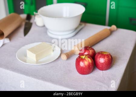 Äpfel, Nudelholz, elektronische digitale Küchenwaage auf dem Tisch. Vorbereitung zum Kochen von Gebäck Stockfoto