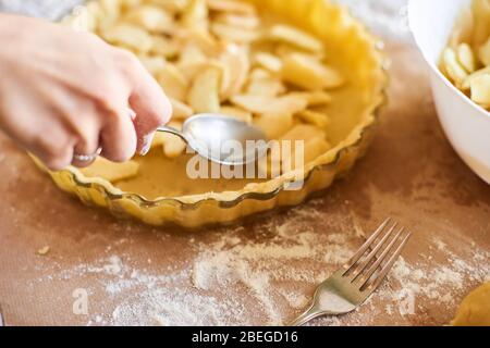 Home Backen von Urlaub klassische süße Kuchen. Frau Hände Fixierung Teig in einem Tablett und Kürbiskuchen Zutaten. Zubereitung traditioneller Desserts Stockfoto