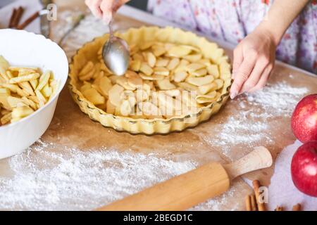 Home Backen von Urlaub klassische süße Kuchen. Frau Hände Fixierung Teig in einem Tablett und Kürbiskuchen Zutaten. Zubereitung traditioneller Desserts Stockfoto