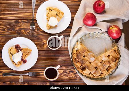 Leckere hausgemachte Apfelkuchen, in Scheiben mit Eis. Äpfel. Teller, Leinentuch Holzhintergrund Draufsicht Stockfoto