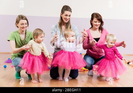 Drei Mädchen in rosa Röcken lernen zu gehen Stockfoto