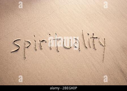 Einfache nicht konfessionelle Spiritualität Nachricht handgeschrieben in Kleinbuchstaben auf texturierten Sandstrand Stockfoto