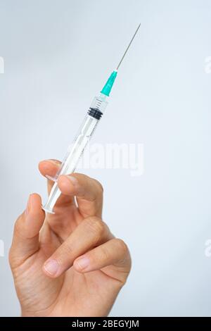 Spritze, die von einer Hand mit weißem Hintergrund gehalten wird Stockfoto