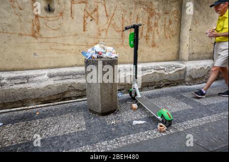 PRAG - 20. JULI 2019: Ein Elektromoped zum Mieten, der neben einem überlaufenen Müllbehälter auf einer Straße in Prag geparkt ist Stockfoto