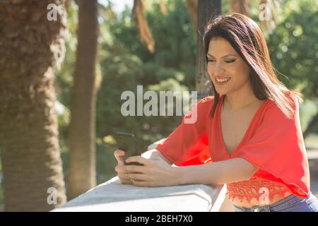 Frau lächelt, während sie ihr Handy benutzt Stockfoto