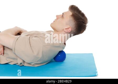 Schöner Mann zeigt Übungen mit dem Ball mit Spikes für eine myofascial Release Massage von Triggerpunkten. Massage der Wirbelsäulenmuskulatur. Isoliert auf w Stockfoto