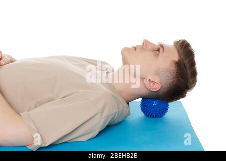 Schöner Mann zeigt Übungen mit dem Ball mit Spikes für eine myofascial Release Massage von Triggerpunkten. Massage des Nackenmuskels. Isoliert auf wh Stockfoto