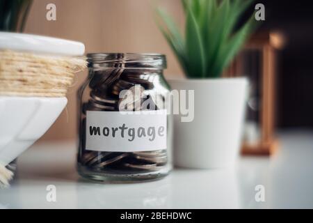 Hypothek Sparkonzept - Glas mit Münzen und Inschrift. Nahaufnahme. Stockfoto