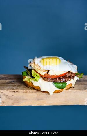 Eierburger mit Rindfleisch, Tomaten und Käse auf Holztisch serviert. Kopierbereich. Stockfoto