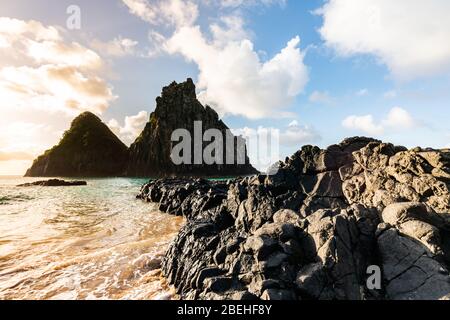 Schöner Sonnenuntergang am Strand Cacimba do Padre mit Blick auf den Dois Irmaos Hügel und türkisblaues Wasser, bei Fernando de Noronha, UNESCO-Weltkulturerbe Stockfoto