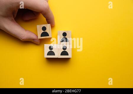 Gefeuerte Konzept - Hand hält Holzblock mit abstrakten Arbeiter auf einem gelben Hintergrund. Nahaufnahme. Stockfoto