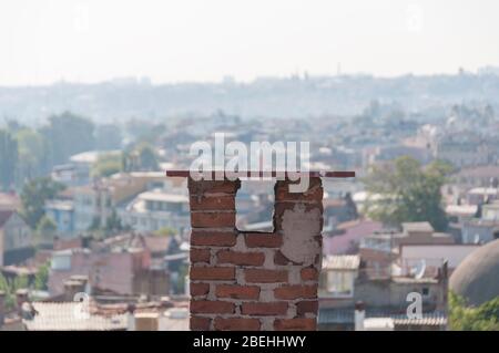 Roter Ziegelkamin mit europäischem Stadtbild im Hintergrund. Wohngebäude architektonische Detail Stockfoto