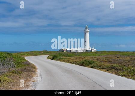Weißer Leuchtturm gegen blauen Himmel mit geschwungenen Straße im Vordergrund. Seal Point Lighthouse am Cape St Francis in Südafrika Stockfoto