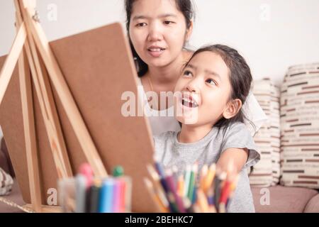 Mutter und Tochter teilen ihre Ferien. Kinder lernen Malen mit Eltern. Asiatische kleine Mädchen Zeichnung mit Glück. Stockfoto