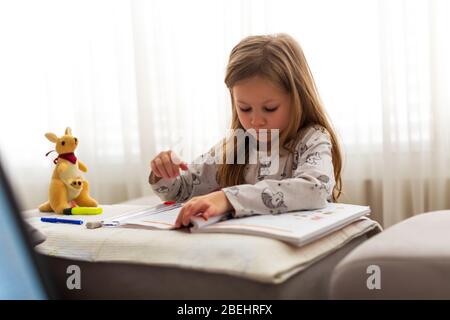 Kleines sechsjähriges Mädchen, das Hausaufgaben zu Hause macht Stockfoto