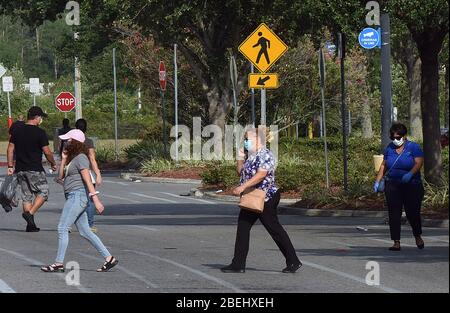 Kissimmee, Vereinigte Staaten. April 2020. 13. April 2020 - Kissimmee, Florida, Vereinigte Staaten - Menschen tragen Gesichtsmasken außerhalb eines Geschäfts in Kissimmee, Florida am 13. April 2020, dem ersten Tag, dass lokale Beamte in Osceola County, Florida in der Nähe von Orlando machte das Tragen von Gesichtsbezügen in der Öffentlichkeit obligatorisch, um die Ausbreitung der COVID-19 Pandemie einzudämmen. Kredit: Paul Hennessy/Alamy Live News Stockfoto