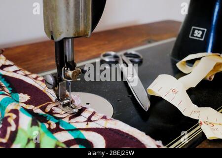 Nahaufnahme einer Vintage Nähmaschine mit Stoff, Schere und Maßband Stockfoto