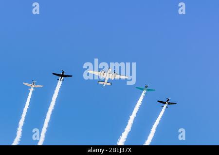 Historische Flugzeuge fliegen in Formation, hinterlassend eine weiße Rauchspur; Kalifornien Stockfoto