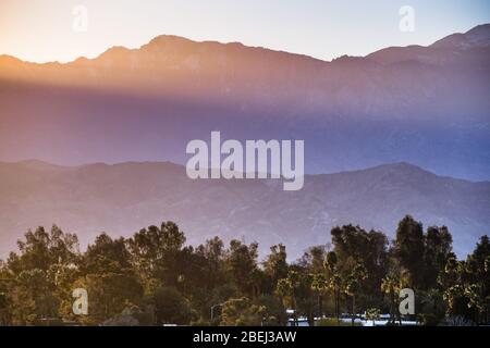 Sonnenuntergang Landschaft im Coachella Valley, mit Sonnenstrahlen, die auf den felsigen Bergrücken der San Jacinto Berge, Palm Desert, Kalifornien, leuchten Stockfoto