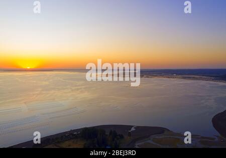Luftaufnahme mit dem Meer bei Sonnenuntergang. Lachs- und Muschelfarmen im Meer Stockfoto