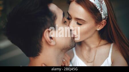 Schöne Ingwer Frau mit Sommersprossen küssen ihren Liebhaber während eines Spaziergangs im Park Stockfoto