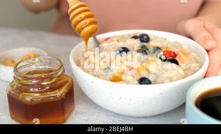 Haferbrei mit Honig und Beeren. Hinzufügen von natürlichem Honig zum Frühstück Hafer Schüssel. Diät, sauberes Esskonzept Stockfoto