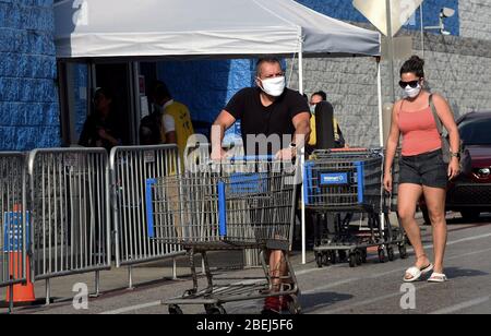 Kissimmee, Vereinigte Staaten. April 2020. Die Menschen tragen Gesichtsmasken vor einem Geschäft am ersten Tag, dass lokale Beamte in Osceola County, Florida in der Nähe von Orlando das Tragen von Gesichtsbezügen in der Öffentlichkeit obligatorisch in dem Bemühen, die Ausbreitung der COVID-19 Pandemie einzudämmen. Quelle: SOPA Images Limited/Alamy Live News Stockfoto