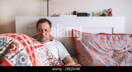 Mann arbeitet und schaut sich das Telefon im Bett an. Arbeiten Sie online von zu Hause aus. Quarantäne, Selbstisolierung, Depression, soziale Distanz, psychisches Gesundheitskonzept. Stock Foto. Stockfoto