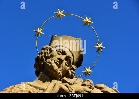 Detail aus barockem Stein St. Nepomuk Statue mit einer Sternenkrone auf Steinbrücke, Tschechische Republik, sonniger Tag mit blauem Himmel Stockfoto