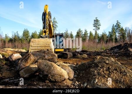 Gelbe Bagger Bau einer Straße tief im Wald. Rusko, Finnland. Stockfoto