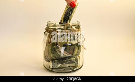 Glasgefäße gefüllt mit Dollarscheinen, Einsparungen im Glasbecher, Geld isoliert auf Weiß Stockfoto