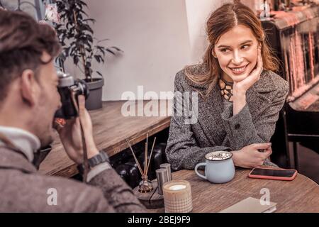 Schöne Frau posiert für ihren Freund unter ihre Fotos im Café Stockfoto