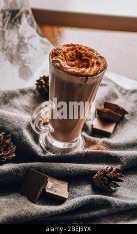 Ein Glas Latte Macchiato, köstliche heiße Schokolade, eine Tasse Kaffee mit Zimt, Schokolade und Sahne Stockfoto