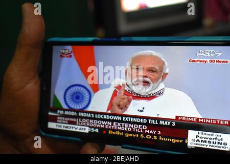 Kalkutta, Indien. April 2020. Die Menschen zeigen Narendra Modi's Rede auf ihrem Handy in Kalkutta, Indien. Indiens Lockdown von Covid-19 wurde bis zum 3. Mai verlängert, sagte Premierminister Narendra Modi in einer Ansprache an die Nation. Die anfängliche 21-tägige Sperrung sollte am Dienstag enden. Modi erklärte, dass die Lockdown, sowie andere soziale Distanzierungsmaßnahmen, dem Land trotz der angefallenen wirtschaftlichen Kosten zugute gekommen sind. (Foto von Biswarup Ganguly/Pacific Press) Quelle: Pacific Press Agency/Alamy Live News Stockfoto