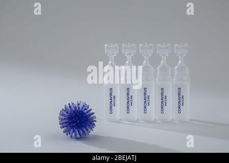 Abstraktes Modell der Virusinfektion und Medizin in einer Ampulle auf grauem Hintergrund. Auf Ampullen geschrieben Coronavirus-Impfstoff. Pandemierisiko. Stockfoto