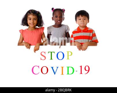 Gruppe von multirassischen Kindern zeigt "Stopp Covid-19" . Konzept 2019-NCoV. Ausbruch des Corona-Virus. Text auf dem Board-Kopierbereich Stockfoto