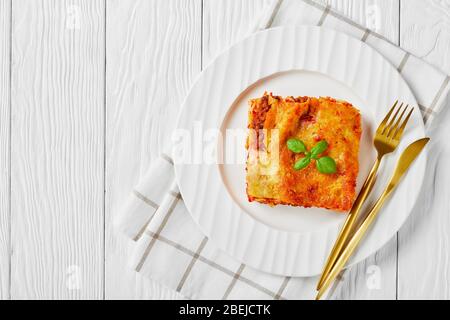 Italienische Küche: Gebackene Cannelloni mit Hackfleisch und Tomatensauce mit Mozzarella-Käse und frischem Basilikum auf einem weißen Teller auf weißem wo gefüllt Stockfoto
