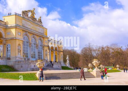 Wien, Aussia - 3. April 2015: Die Gloriette im Schlossgarten Schönbrunn vor dem wolkigen blauen Himmel. Touristen, die herumlaufen. Stockfoto