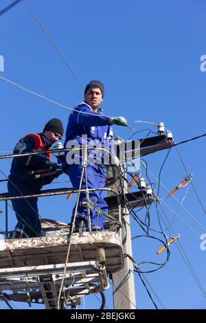 Krasnodar, Russland - 2. März 2020: Männliche Elektriker tauschen elektrische Leitungen an Polen Stockfoto