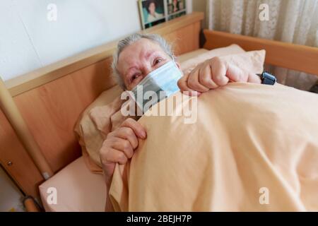Eine alte Frau liegt mit einer Gesichtsmaske in ihrem Bett Stockfoto