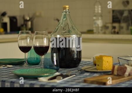 Tischset mit Geschirr, Gläsern und einer Flasche Rotwein in der Nähe von Salami und Brot (Pesaro, Italien, Europa) Stockfoto