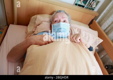 Eine alte Frau liegt mit einer Gesichtsmaske in ihrem Bett Stockfoto