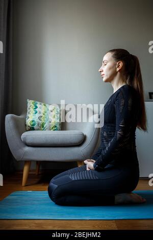 Junge Frau, die Yoga in Entspannung praktiziert Pose zu Hause während der Quarantäne Stockfoto