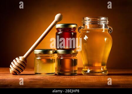 Auf dem rustikalen Tisch verschiedene Arten von Honig in Gläsern mit Schöpfkelle. Stillleben Stockfoto